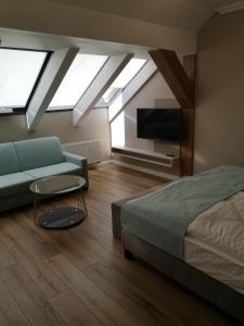 a bedroom with a bed and a couch and a tv at Hotel Blaha Lujza in Balatonfüred