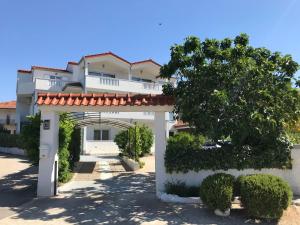 a large white building with a gate and bushes at Apartments Bumbar in Rogoznica