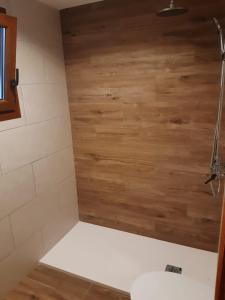 ein Badezimmer mit einer Holzwand neben einem WC in der Unterkunft Moderno apartamento con vista a la montaña in Port de Sóller