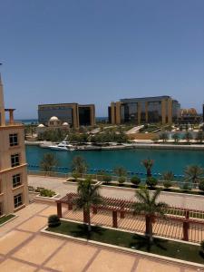 Vista al árido de un edificio con un banco y una masa de agua en شقة مارينا البيلسان - عائلات فقط, en King Abdullah Economic City