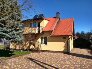 une maison avec un toit orange et une allée dans l'établissement Pokoje nad morzem Mikoszewo, à Mikoszewo