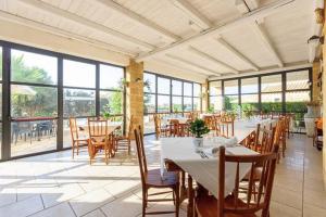 a dining room with tables and chairs and windows at Podere Fossarunza di Carlo Manzo in Marsala