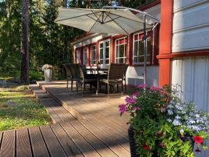 eine Holzterrasse mit einem Tisch, Stühlen und einem Sonnenschirm in der Unterkunft Sinisalu Apartments in Käsmu