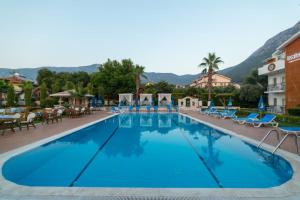 a pool at a hotel with chairs and mountains in the background at İksirci Baba Hotel in Oludeniz