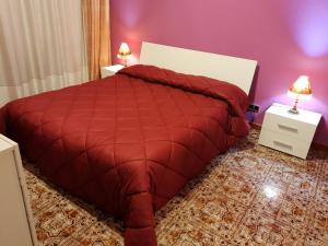 a red bed with a red comforter in a bedroom at Lorena Loft in Locri