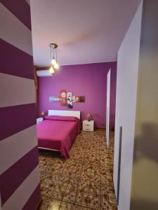 a purple bedroom with a bed and purple walls at Lorena Loft in Locri