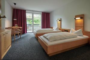 una camera d'albergo con due letti e un tavolo di Hotel Bannwaldsee a Halblech