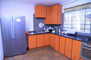 Union Guesthouse في بريتوريا: مطبخ مع دواليب خشبية وثلاجة حديد قابلة للصدأ