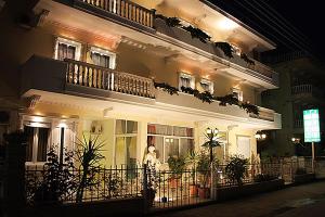 a building at night with a man standing in front of it at Villa Niki in Olympiaki Akti