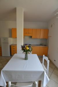 una cocina con una mesa blanca con un jarrón de flores. en Appartamenti Venere, en San Vincenzo