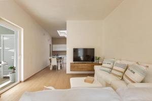 a living room with a white couch and a television at La Giada by Perle di Puglia in Maruggio