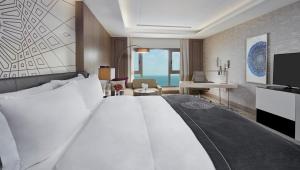 InterContinental Doha Beach & Spa, an IHG Hotel في الدوحة: غرفة الفندق بسرير كبير ومكتب