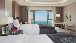 ドーハにあるInterContinental Doha Beach & Spa, an IHG Hotelのベッド2台が備わる海の景色を望むホテルルームです。