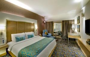 Cette chambre comprend un grand lit et un bureau. dans l'établissement Pride Plaza Hotel, Ahmedabad, à Ahmedabad