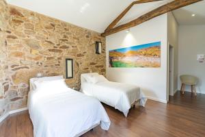 2 Betten in einem Zimmer mit einer Steinmauer in der Unterkunft GOLDNATURE in Gondomar