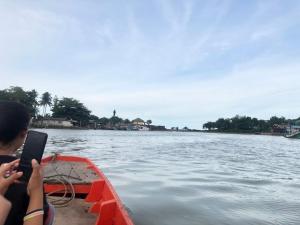 a person in a boat on the water with a tablet at Chaiyai River Front Hotel in Sichon