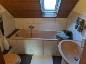 y baño con bañera y lavamanos. en Ferienwohnung Zundel, en Neu-Anspach