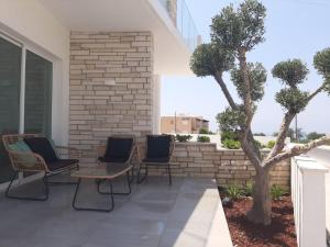 um pátio com cadeiras e uma árvore num edifício em Melanos Fully Renovated TownHouse with Private Pool em Pafos