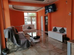 uma sala de estar com paredes cor de laranja e uma mesa e cadeiras em Къща за гости Диана ДИК em Kiten