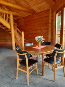 una mesa de madera con sillas y un jarrón de flores en Ośrodek wypoczynkowy "Źródła Dobrej", en Olesno