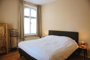 Schlafzimmer mit einem Bett mit weißer Bettwäsche und einem Fenster in der Unterkunft Vakantiewoning Villa Elena in Nieuwpoort