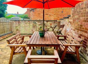 a wooden table with a red umbrella on a patio at Cotswold Place in Cirencester