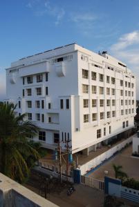 a white building with a palm tree in front of it at Hotel Royal Park Kakinada in Kākināda