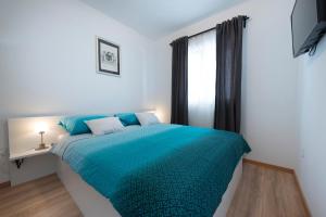 1 dormitorio con cama azul y ventana en Holiday Home Lana, en Supetar