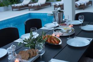 una mesa con comida y copas de vino junto a una piscina en Holiday Home Lana, en Supetar