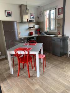 eine Küche mit einem Tisch und 4 roten Stühlen in der Unterkunft Appartement Résidence Saint Jours - Centre ville in Vieux-Boucau-les-Bains