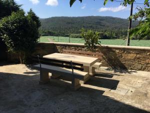 a bench sitting next to a wall with a view of a field at Casa do Grallo in Corcoesto