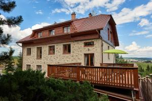 a house with a wooden deck and an umbrella at Villa LUPU in Smižany