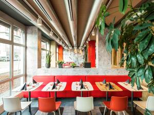 a restaurant with red tables and chairs and plants at ibis Hotel München Garching in Garching bei München
