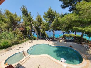 a swimming pool with chairs and trees and the ocean at Evripidis Hotel in Afitos