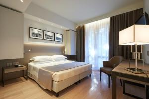 a bedroom with a bed and a desk and a chair at Park Hotel Chianti in Tavarnelle Val di Pesa