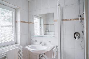 La salle de bains blanche est pourvue d'un lavabo et d'un miroir. dans l'établissement Landhaus Martinus, à Sölden