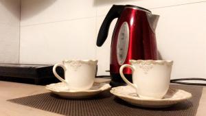 dwie filiżanki herbaty i dzbanek do kawy na ladzie w obiekcie Pokoje Mrągowo w mieście Mrągowo