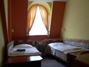 two beds in a room with a window at Hotel Armales in Stakčín