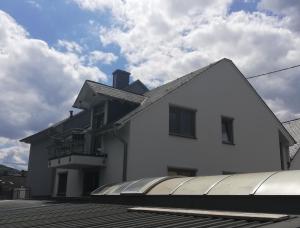 ein weißes Haus mit einem Gebäude mit einem Balkon in der Unterkunft Ferienwohnung Weißburgunder in Lieser