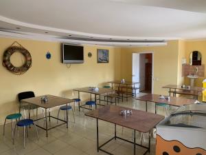 a dining room with tables and chairs and a tv at Миндаль in Zatoka