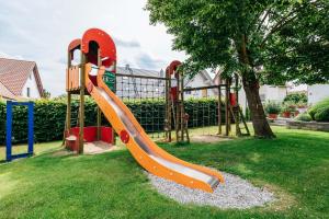 a playground with an orange slide in the grass at Gasthaus Hotel Ostermeier in Attenkirchen