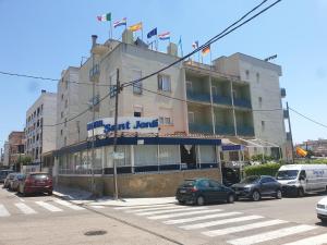 un edificio con coches estacionados frente a él en Hotel Sant Jordi, en Segur de Calafell