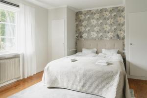 um quarto com uma cama branca e papel de parede floral em Trollnäs Hotell em Svärdsjö