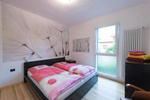 1 dormitorio con cama con sábanas rosas y ventana en Appartement Balcone sul Lago, en Riva del Garda