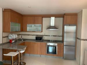 a kitchen with wooden cabinets and a stainless steel refrigerator at Forever FOZ in Foz