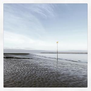 a pole sticking out of the sand on a beach at La Maison de Lilly in Arcachon