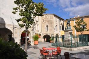 une terrasse avec une table et des chaises devant un bâtiment dans l'établissement Duplex au Coeur de Lunel, à Lunel