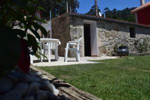 two white chairs and a table in a yard at Pedra da Lan - una casita de piedra in Cangas de Morrazo