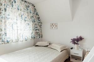 a white bedroom with a bed and a window at Autentic Adorabil Apartment in Albeştii Pămînteni