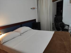 巴西利亞的住宿－Condomínio Metropolitan - Centro de Brasília A216A，卧室配有一张白色的床、一张桌子和一把椅子